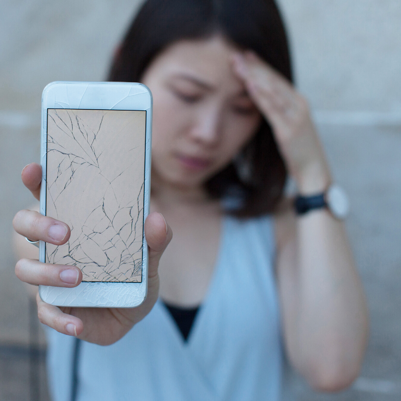 Young woman driver who is upset that her iPhone screen is cracked